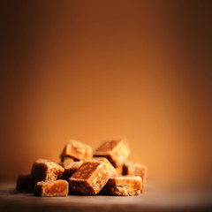 Caramel candies on brown background. Salted caramel pieces and s