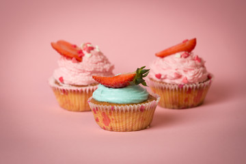 Studio shot of three cupcakes with strawberry on pink background