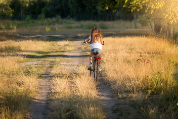 Obraz premium Woman riding bicycle on dirt road at meadow