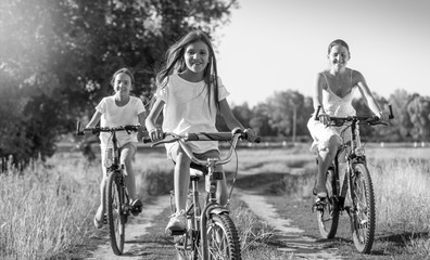 Obraz premium Black and white image of young mother riding on bicycles with tw