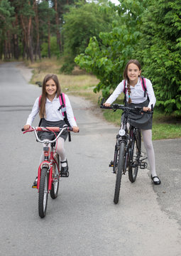 Two schoolgirls riding to school on bicycles