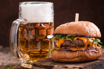 Fresh and tasty hamburger with a beer on a wooden table.