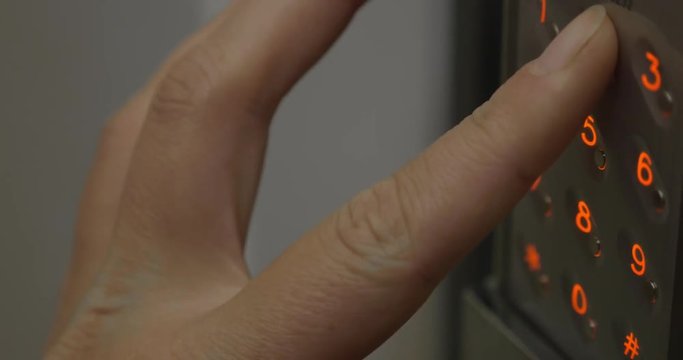 Close-up a woman hand entering unlocking combination on digital security lock