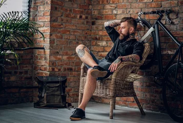Fotobehang The bearded hipster male relaxing in a chair. © Fxquadro
