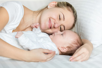 Fototapeta na wymiar Portrait of beautiful smiling woman lying with her cute baby on