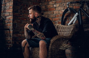 The bearded hipster male relaxing in a chair.