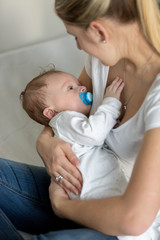 Beautiful mother rocking her cute baby on hands