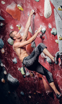 Shirtless male on a climbing wall.