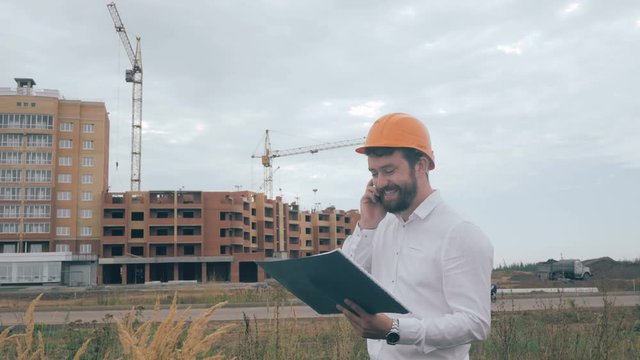 Architect talking on cell phone on a construction site. 4K.