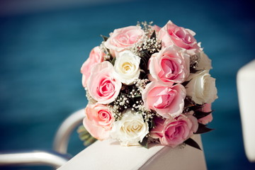 Bouquet of red and white roses flowers on the yacht with blue sea defocused background