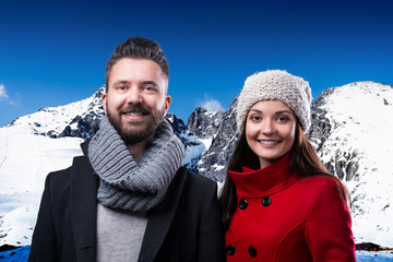 Beautiful young couple in winter clothes in winter mountains