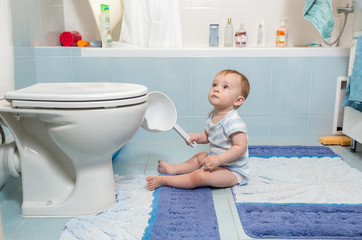 Baby boy sitting on floor at bathroom - obrazy, fototapety, plakaty