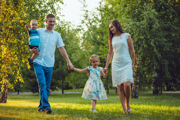 Fototapeta premium Happy young family of four people walking and having fun in the park