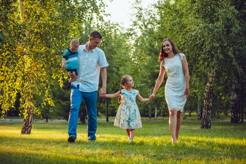Happy young family of four people walking and having fun in the park