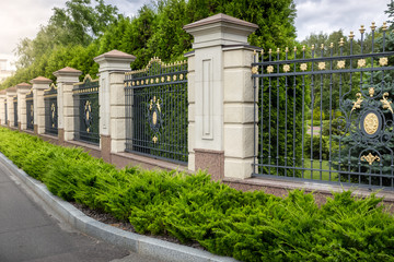 Fototapeta na wymiar Forged fence painted with gold at entrance to luxury villa