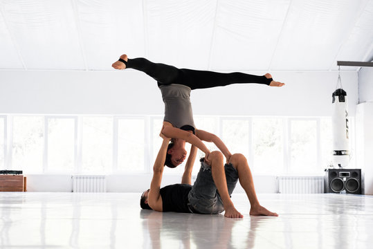 Couple practicing acro yoga in white studio. Acro yoga concept.