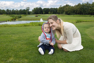 Fototapeta premium 9 months old baby boy sitting on grass at park with his beautifu
