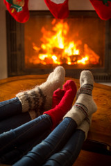 Family wearing woolen socks sitting in chalet by burning firepla