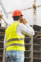 Construction engineer talking by phone and looking on building s