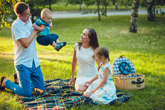 Young happy family of four on picnic in the park