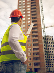 Toned photo of construction engineer pointing at building under