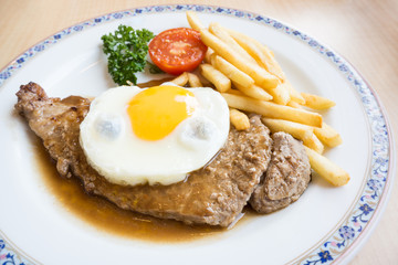 Beef steak with fried egg, fried potatoes and vegetables