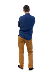 Back view of man . Standing young guy. man in a blue shirt with the sleeves rolled up, standing with her hands folded on his chest.