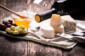 Composition of cheese, berries, bottles and glasses of wine on a wooden table
