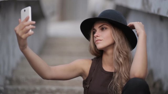 pretty young girl in a black hat pictures of yourself on your smartphone