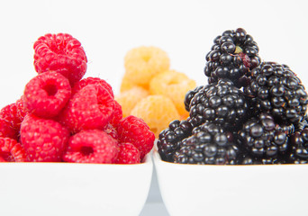 Raspberries and blackberries: bowls of fruit on white background