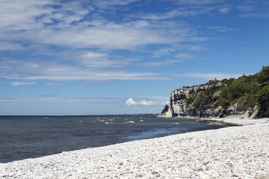 En sandstrand med en klippa i bakgrunden