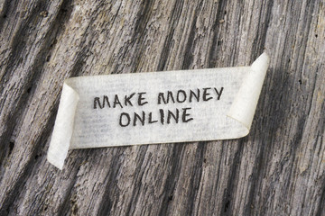 TORN paper with MAKE MONEY ONLINE word on wooden background. 