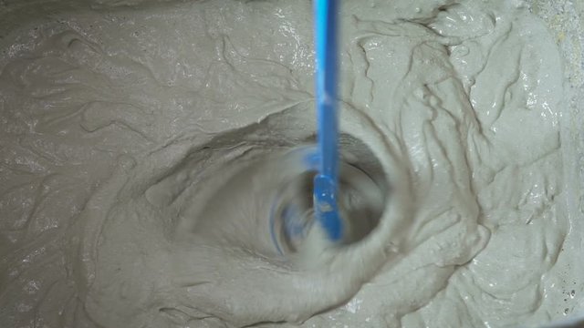 Mixing of a plaster solution by an electric drill.