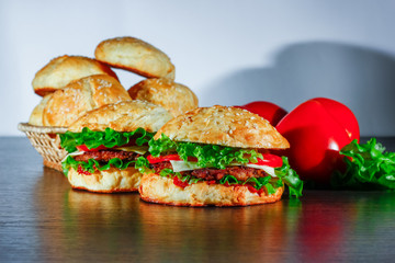 sandwich - hamburger with burger, cheese, tomato, and onion on wooden background
