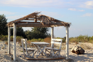 Fototapeta na wymiar Small wooden gazebo with a table and two benches on the beach