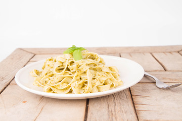 Tagliatelle with pesto decorated with basil on a wooden background