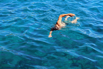 Strong athletic man swimming butterfly style in the sea. Active summer holiday vacation. Sport, healthy lifestyle concept