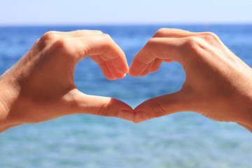 Woman making heart shape with her hands , enjoying summer holiday, vacation. Female, relax, sea, paradise. Love travel concept