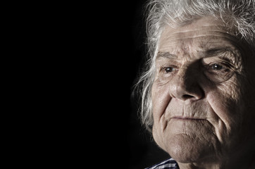 Obraz premium Old woman portrait, close-up face on dark background.