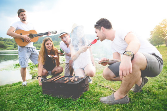 Young couples prepare grill and enjoy in nature near lake