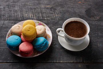 multicolored macaroon on the plate and coffee on the table