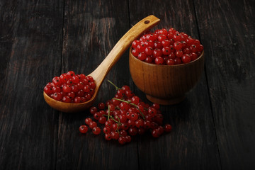 red currant in wooden plate on wooden background