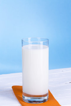 Glas Milch vor hell blau Hintergrund.