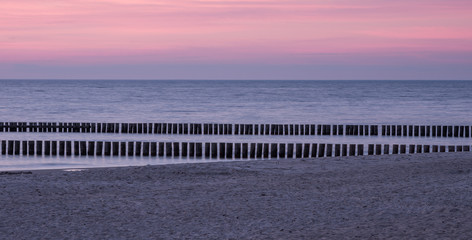 Fototapeta na wymiar Wooden breakwaters - Baltic seascape at sunset, Poland