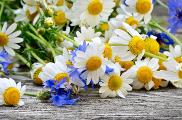 A bouquet of daisies and cornflowers on wooden table. Postcard of wild flowers.