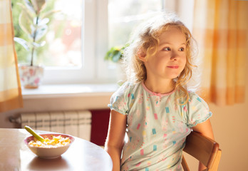 Cute little girl having breakfast, cereals with milk