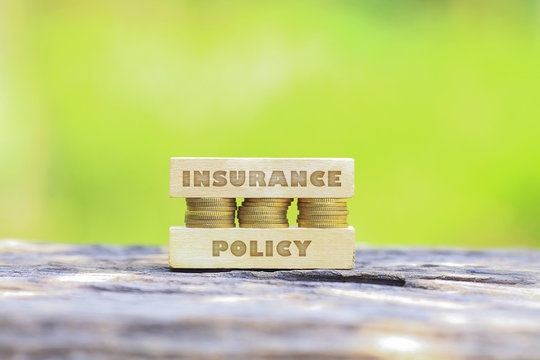 Business Concept - INSURANCE POLICY WORD, Golden coin stacked with woooden bar