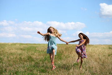 Two little girls running in summer field