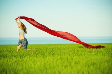 Young lady runing with tissue in green field. Beautiful happy woman walking in the summer rural meadow. Beautiful fit tan girl. Sexy slim model caucasian ethnicity outdoors.
