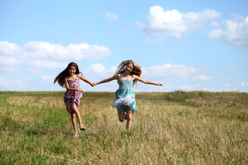 Two little girls running in summer field